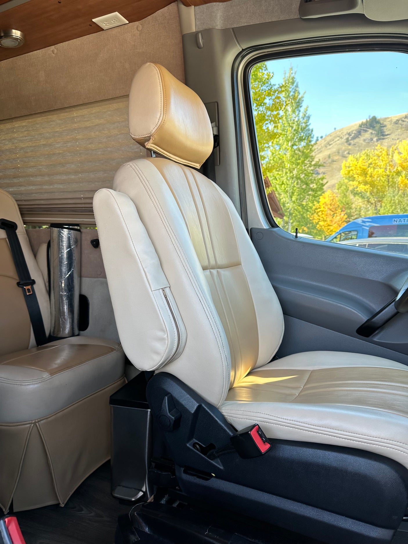 Comfortable two-tone passenger seat in an rv rental, featuring an armrest and scenic autumn mountain views.