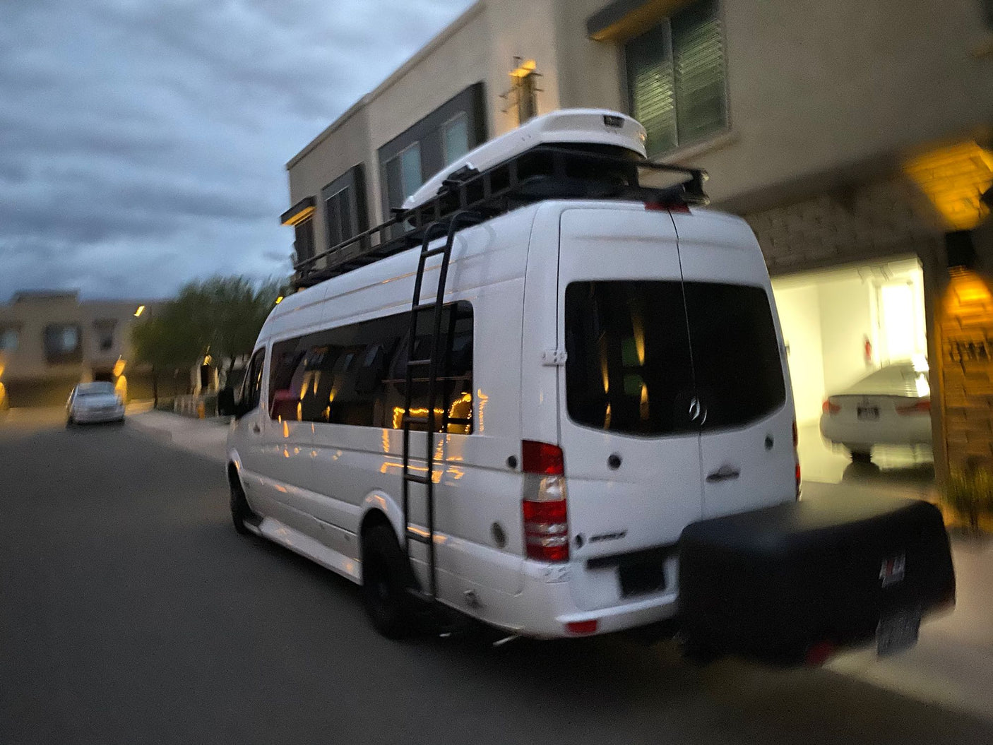 White Sprinter van with roof cargo box and rear carrier, ideal for RV rental road trips. Ready for adventure!