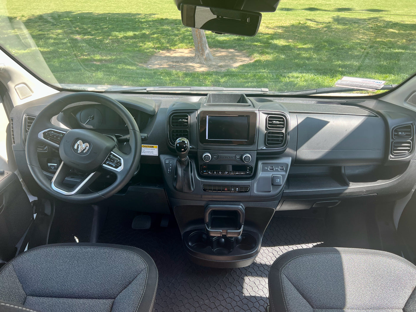 Inside an RV rental van: driver's view of the dashboard, modern steering wheel with Ram logo, and detailed controls for your journey.