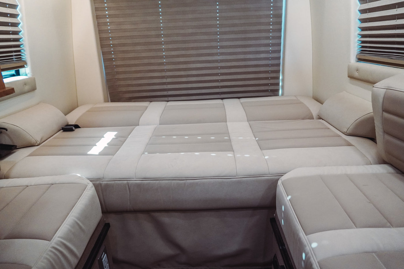 This RV rental features a light-colored, upholstered seating area configured as a bed, with horizontal window blinds. — photo 4
