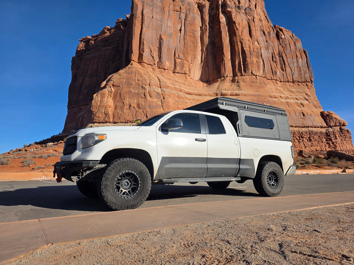 White Tundra with a pop-top camper exploring rugged desert landscapes. An ideal RV rental for your next off-road adventure.