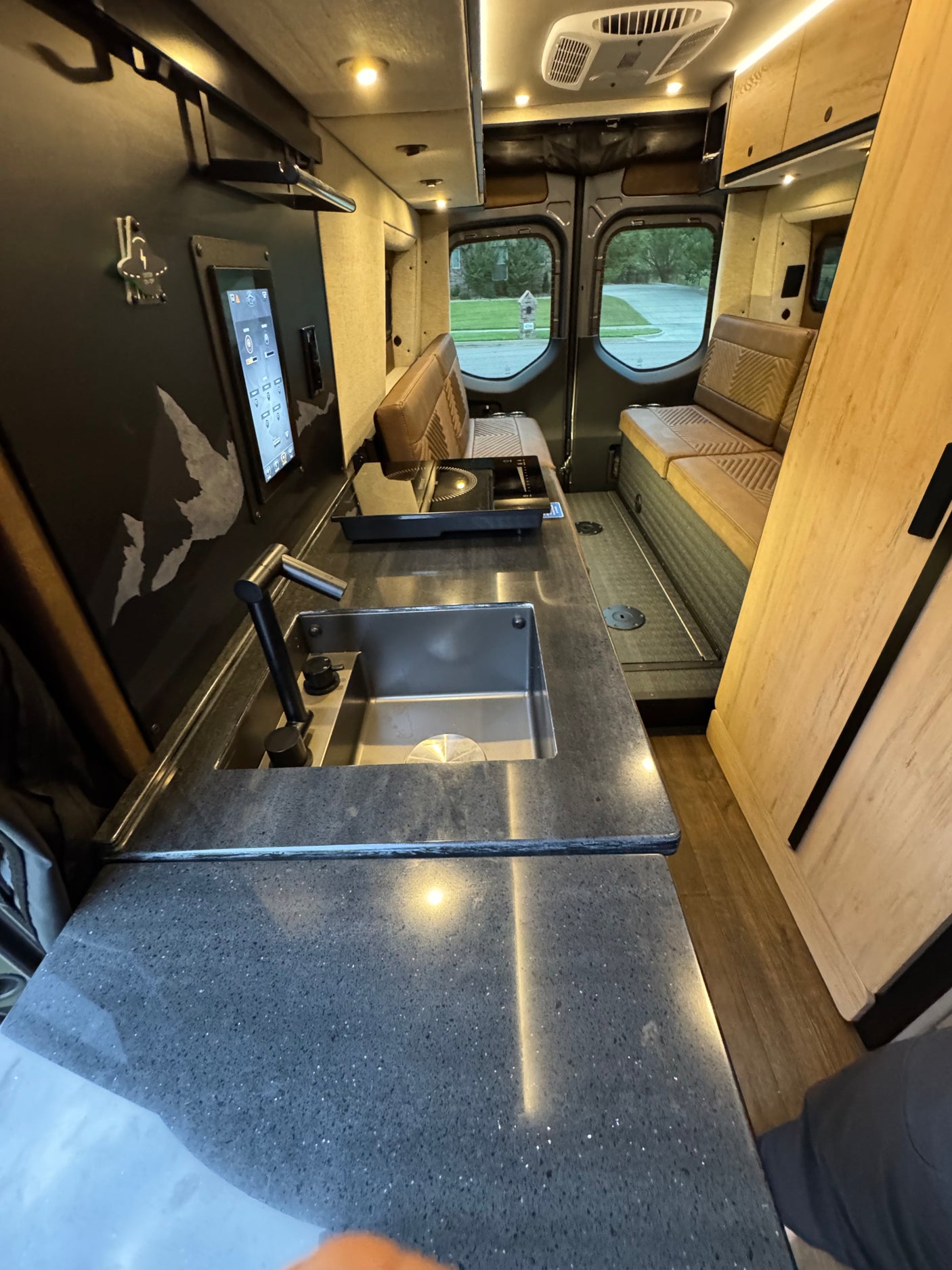 RV rental van interior: sleek kitchen with sink & cooktop, comfy bench seating, and smart controls for your next adventure.