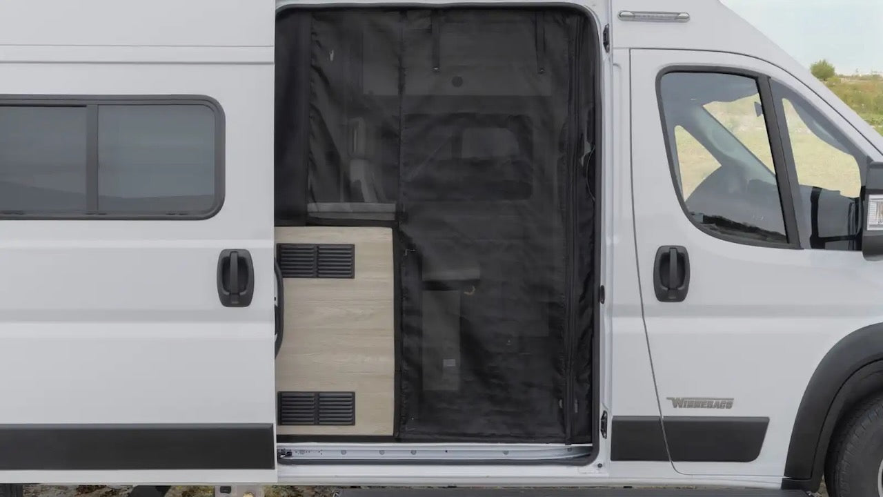 Open white Winnebago camper van RV rental. Side door reveals a black mesh screen & light wood interior, ready for travel.