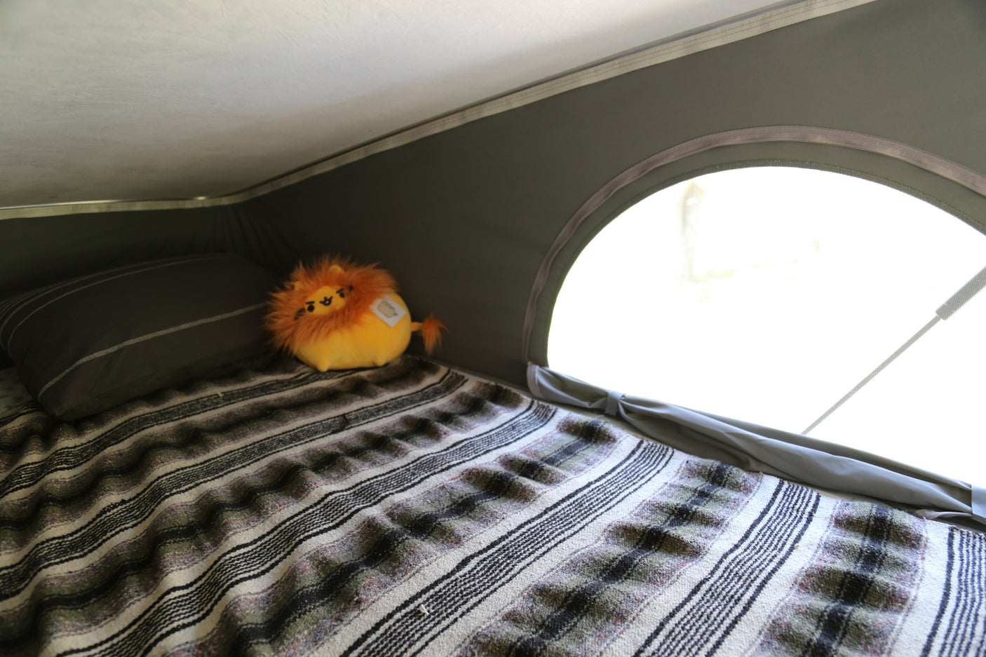 Enjoy a cozy night in your RV rental! This comfy bed with a striped blanket and lion plush awaits your adventure.