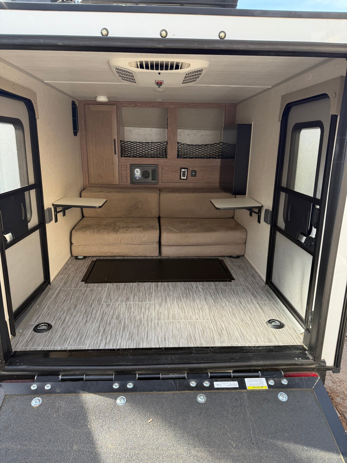 RV rental interior: convertible beds, ceiling AC, built-in storage, and a rear ramp door with floor tie-downs.