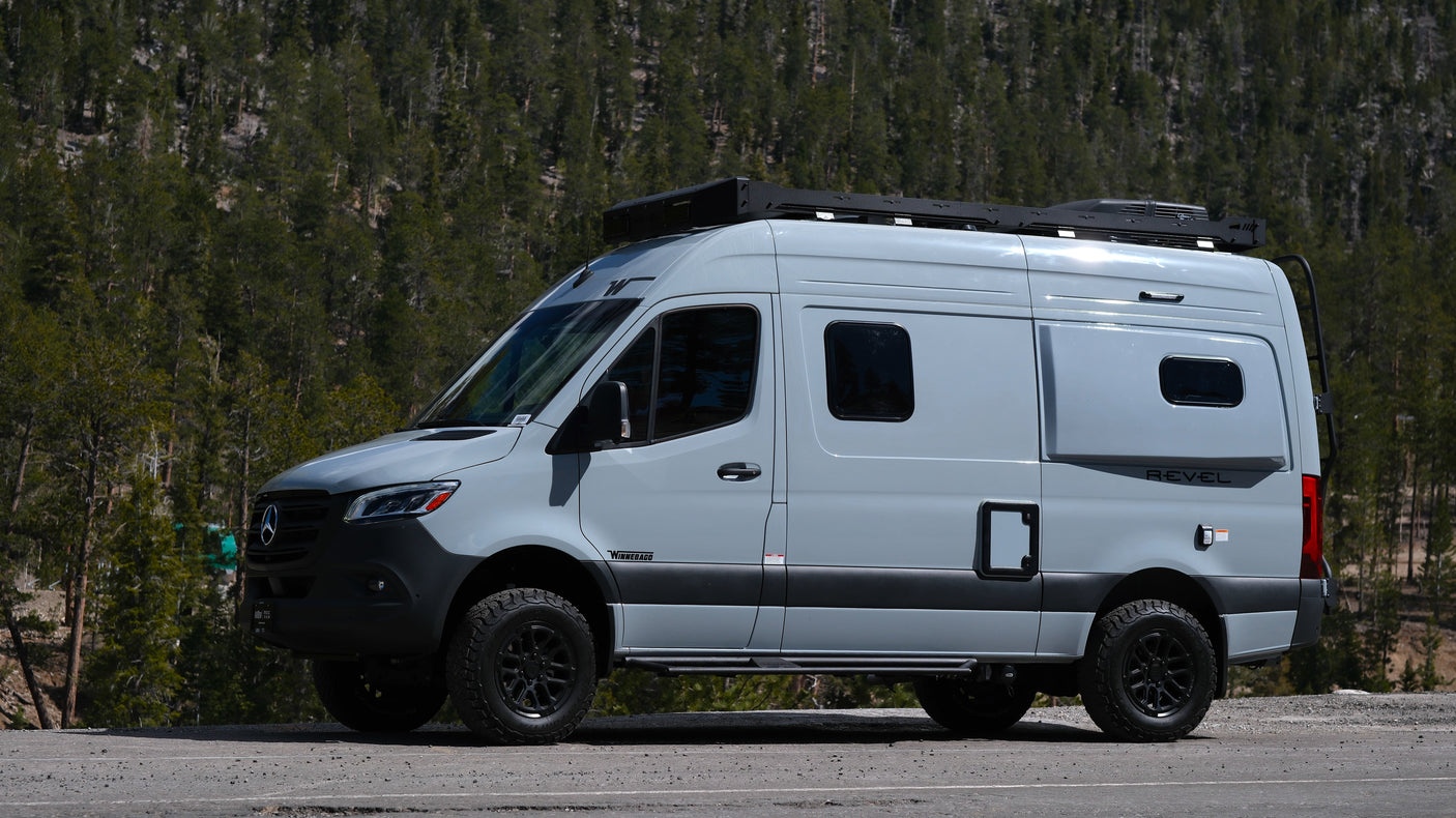 Explore nature with this Winnebago Revel camper van RV rental, parked against a forest backdrop.