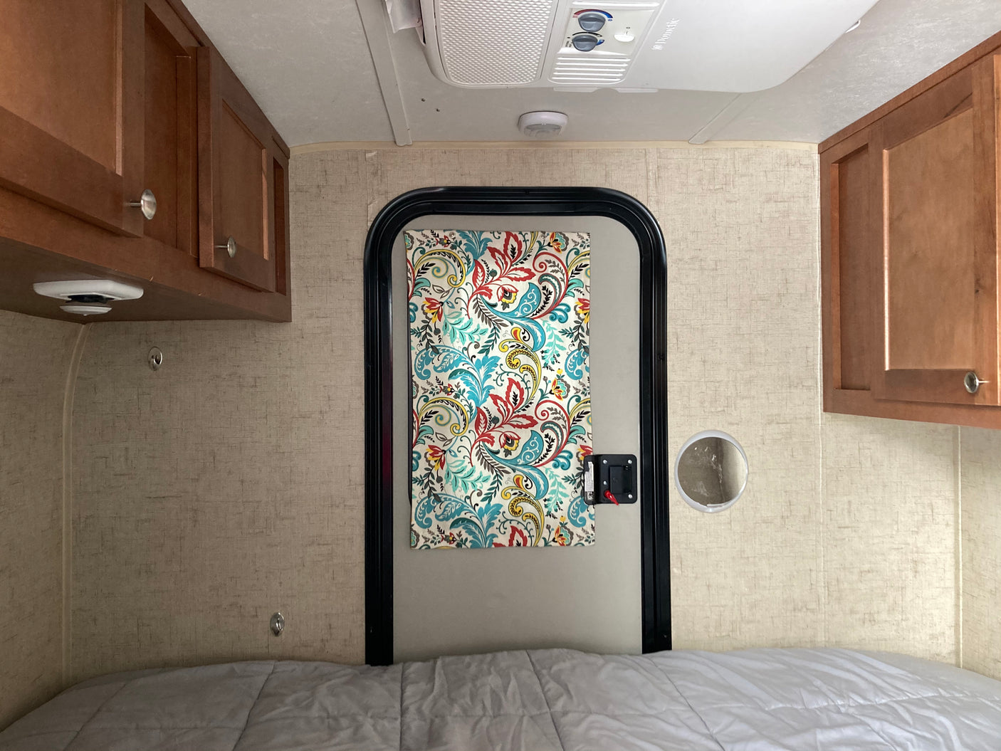 RV rental interior: cozy sleeping area with bed, wood cabinets, and AC.