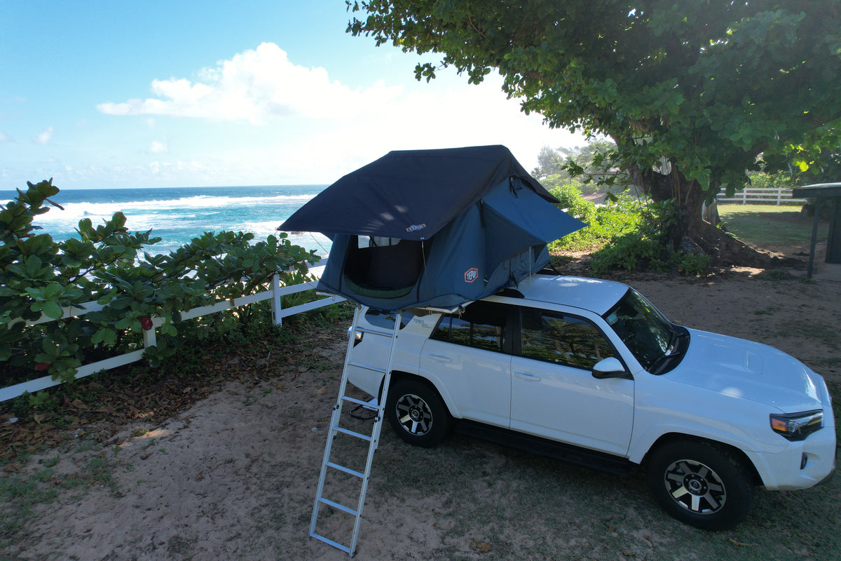 White SUV with rooftop tent setup by the ocean for beach camping. An ideal rv rental for a scenic adventure! — photo 9