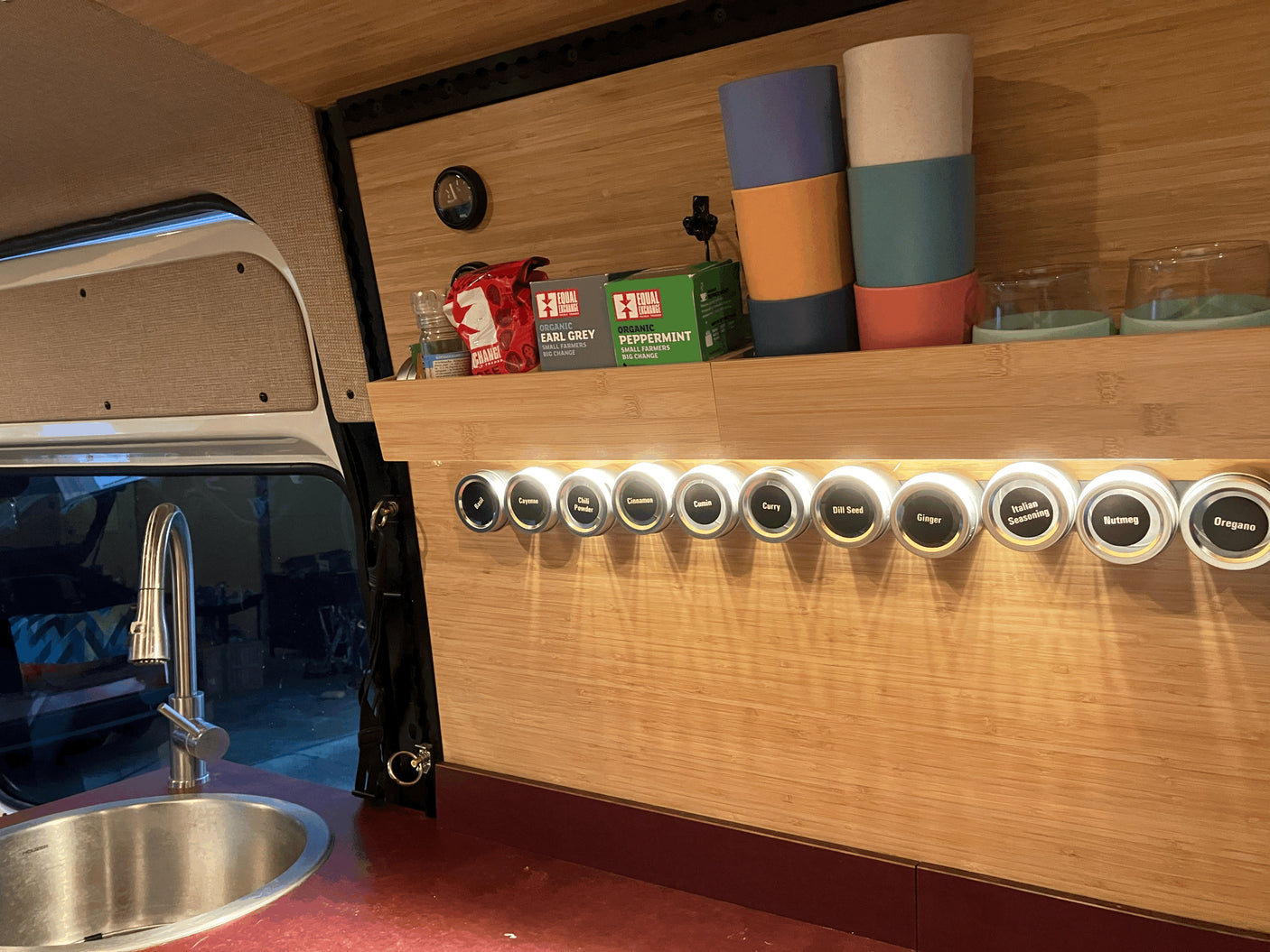 This RV rental's compact kitchen boasts a sink, an organized spice rack, and tea supplies, maximizing small space utility.