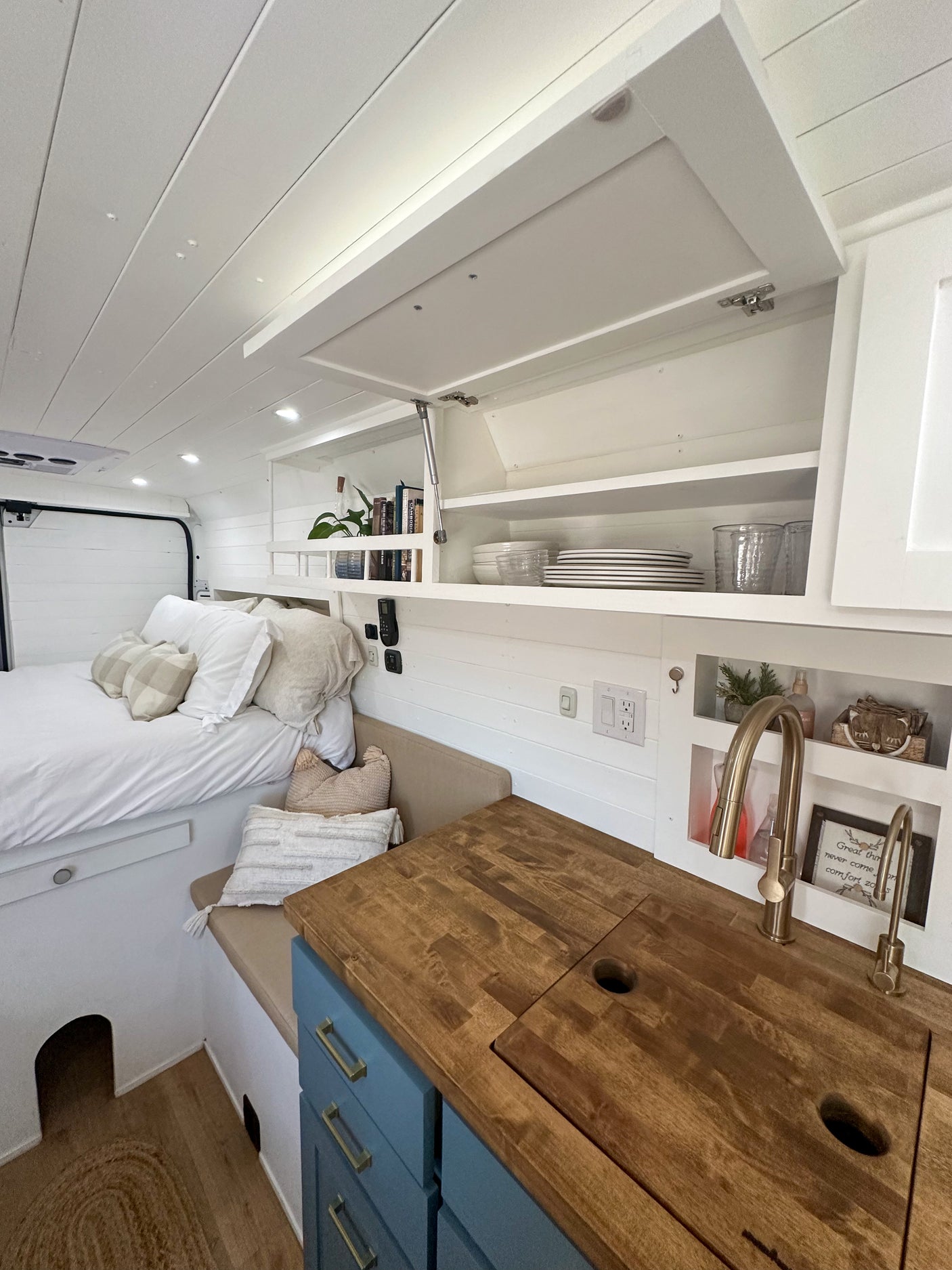 RV rental interior featuring a cozy bedroom, compact kitchen with wood counters, and ample storage for mobile living.