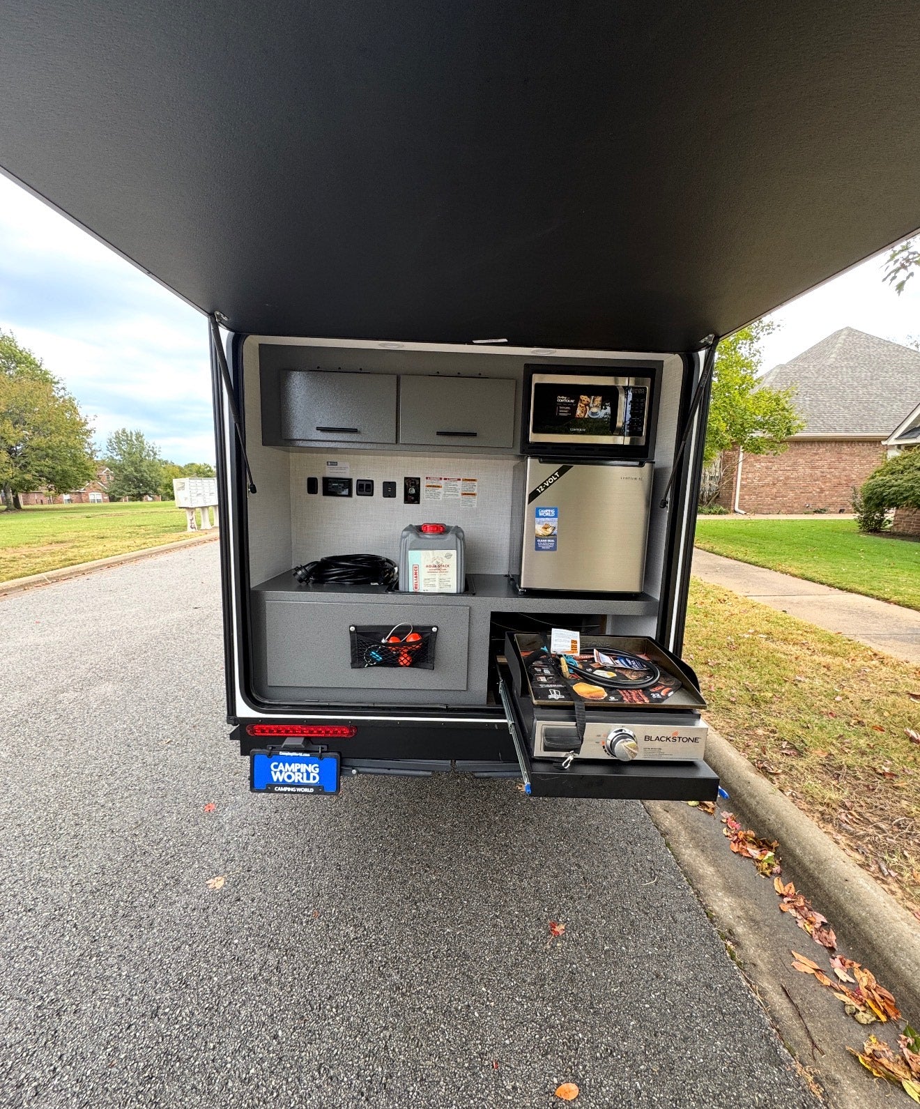 This rv rental boasts an outdoor kitchen, featuring a microwave, fridge, and pull-out Blackstone griddle for convenient camping meals.