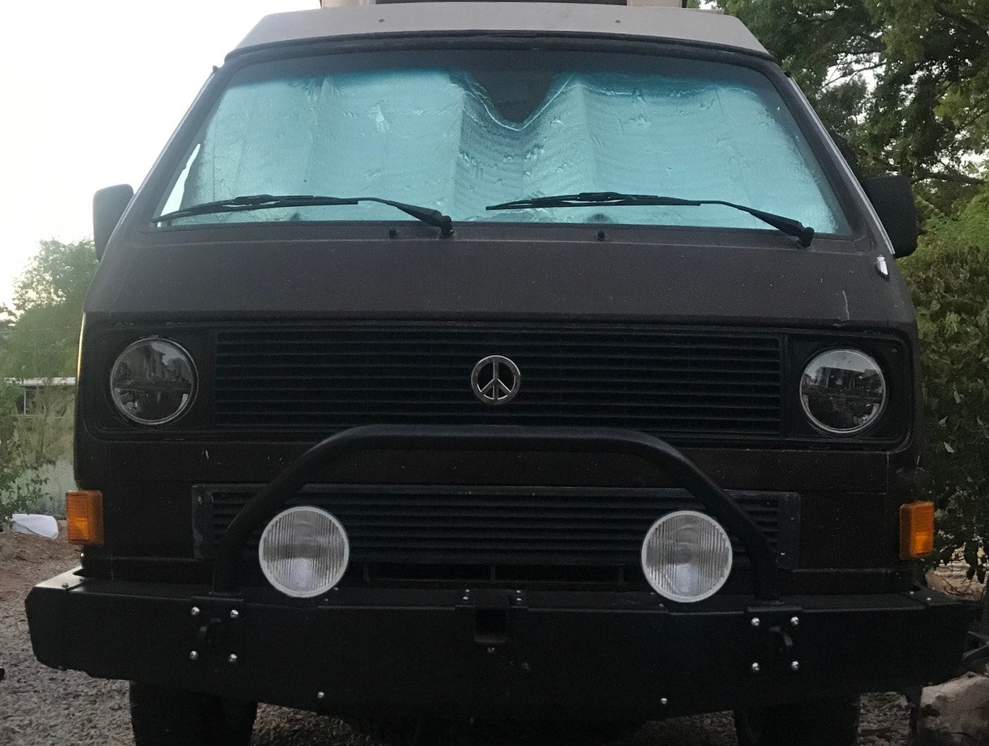 great for an rv rental adventure.|Front view of a dark VW Vanagon camper van with a sunshade