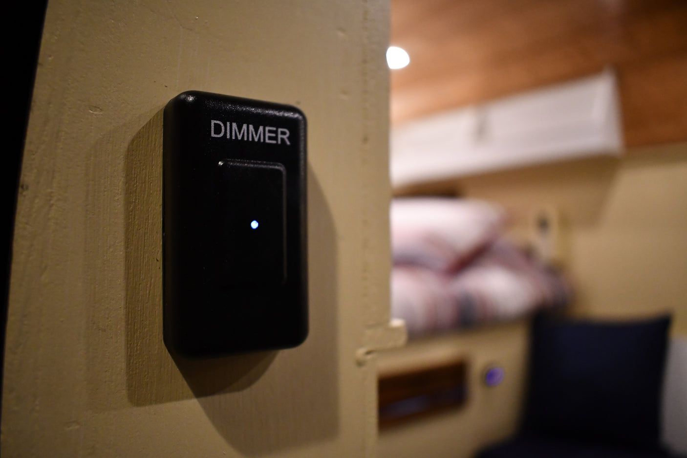 RV rental interior featuring a black "DIMMER" switch with a blue LED light, controlling adjustable lighting for the cozy bunk area.