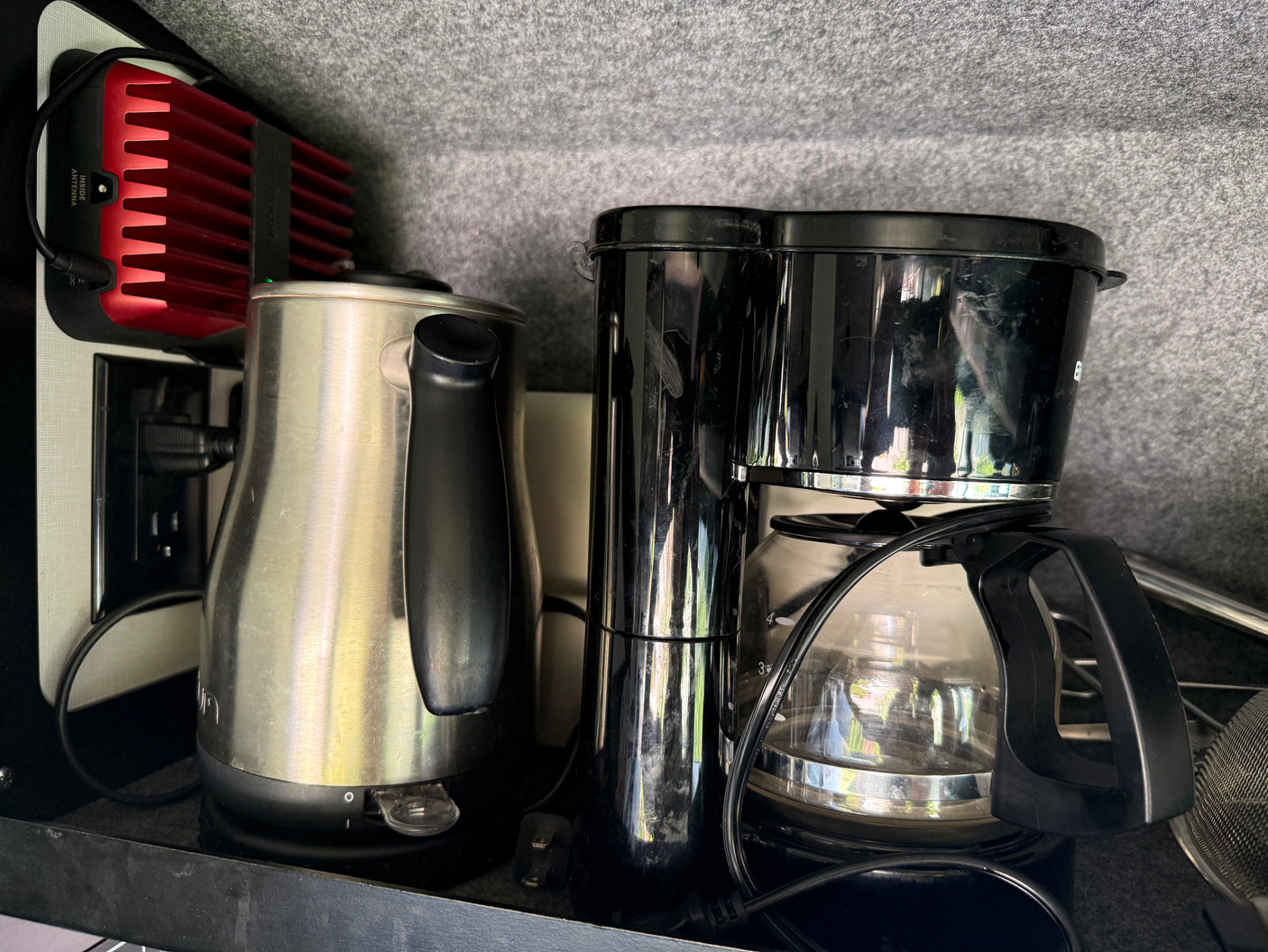 Essential RV rental kitchen appliances: a shiny kettle, coffee maker, and a powerful cell signal booster.