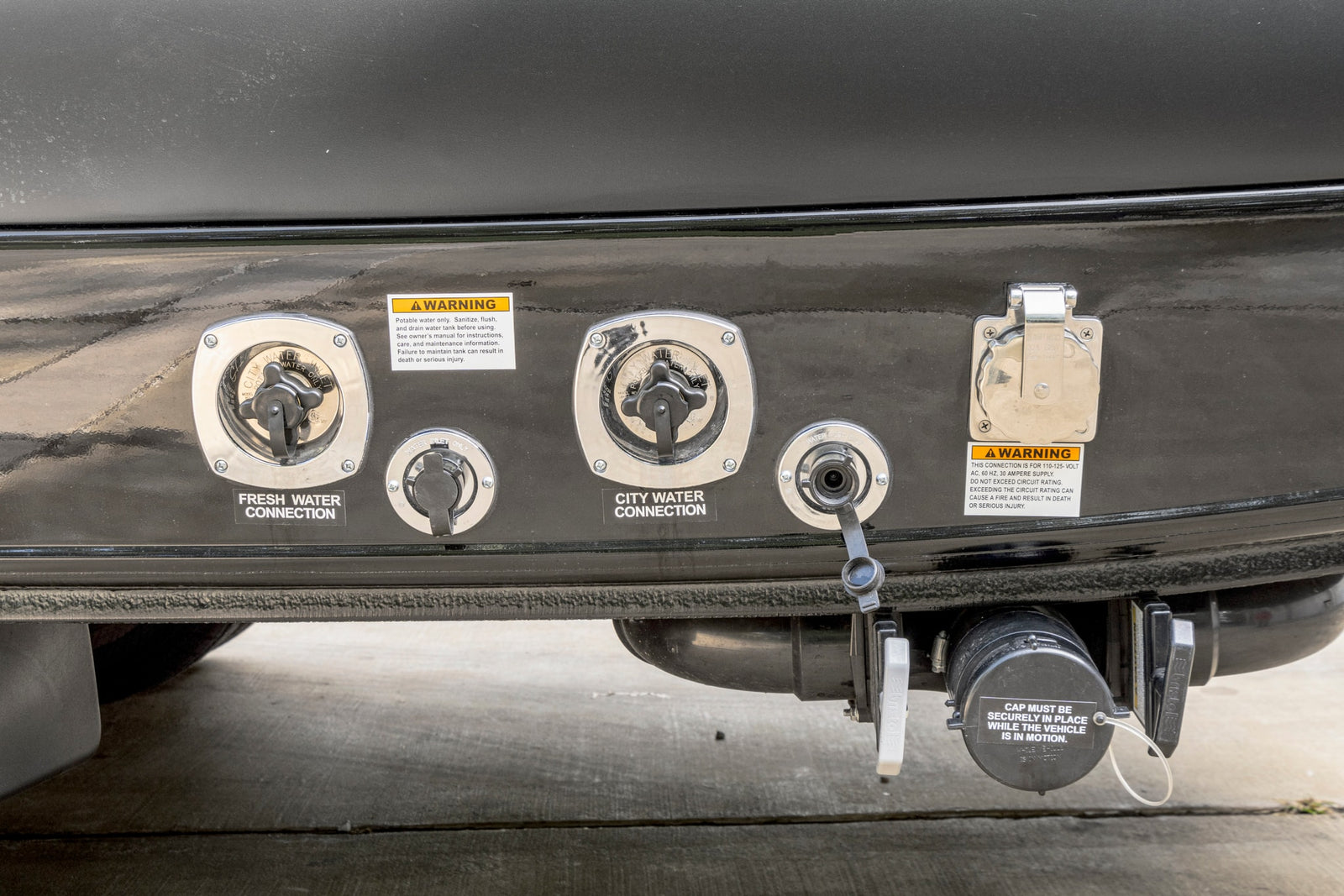 RV rental utility connections: fresh and city water inlets, flush inlet, 30-amp power, and a secure sewer dump cap.
