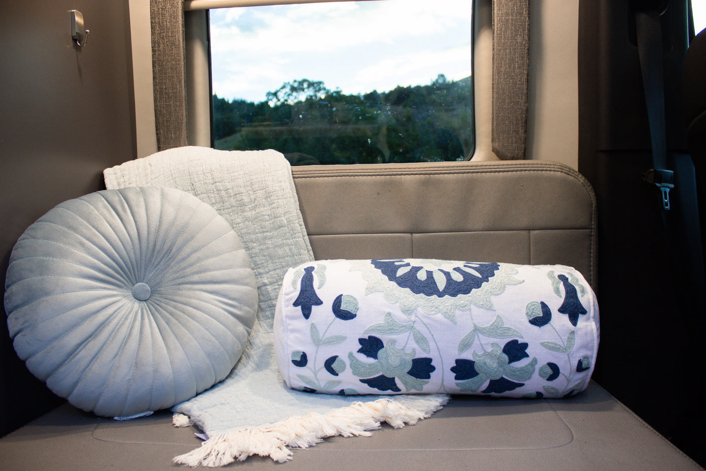 Cozy RV rental interior with decorative pillows, a blanket, and a scenic window view, perfect for travel comfort.
