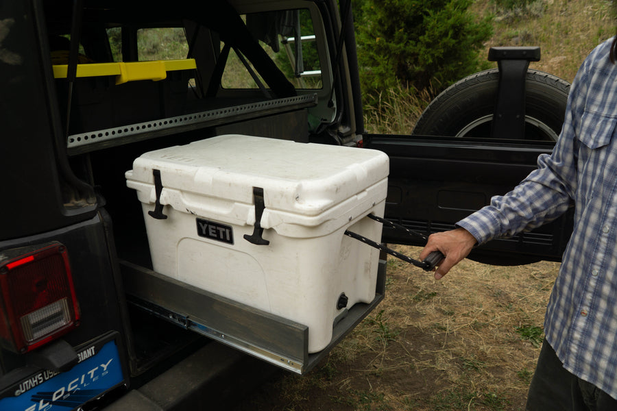 Organized Jeep adventure with an rv rental! Man pulls Yeti cooler from custom slide-out storage system.