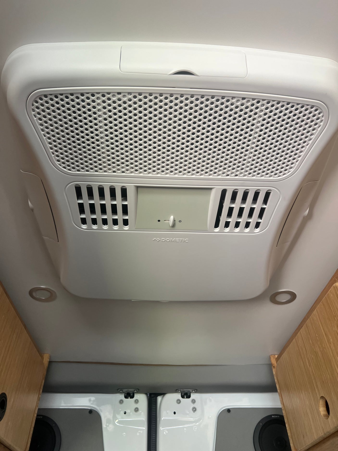 Overhead Dometic climate control unit with air vents & lights in an RV rental, ensuring comfort.