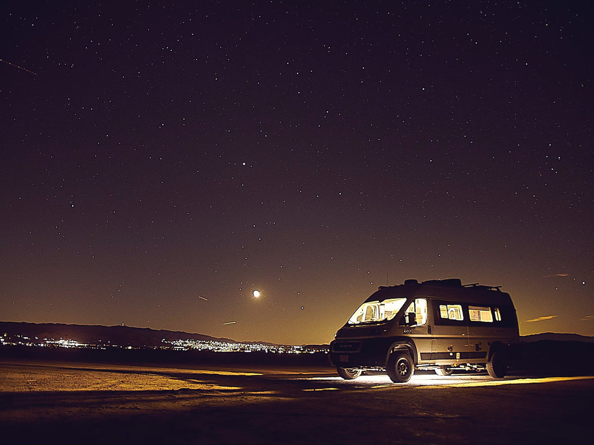 enjoying nature views.|Silver RV rental van parked in a sunny desert landscape with Joshua trees and rocky hills under a clear blue sky.|An RV rental illuminated under a vast — photo 8