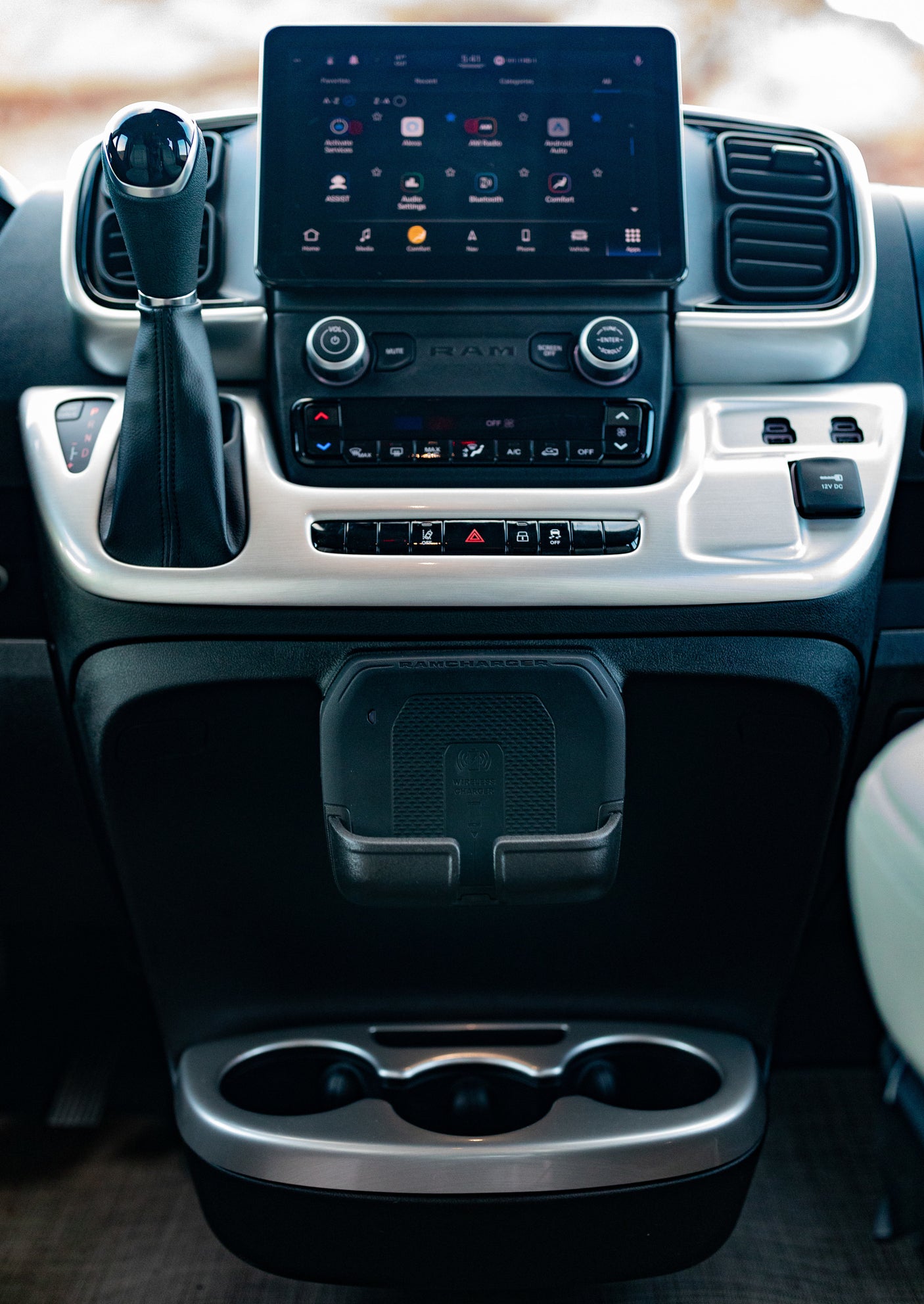 Modern RV rental dashboard: Touchscreen infotainment system, shifter, climate controls, and RAMCHARGER wireless charger.