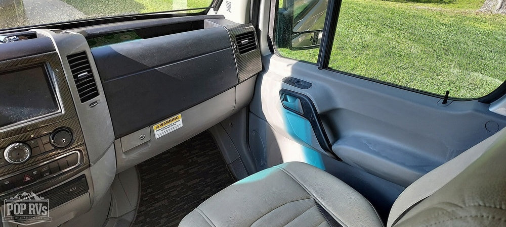 RV rental's passenger cabin, featuring a detailed dashboard, infotainment screen, and door panel. Ready for travel.