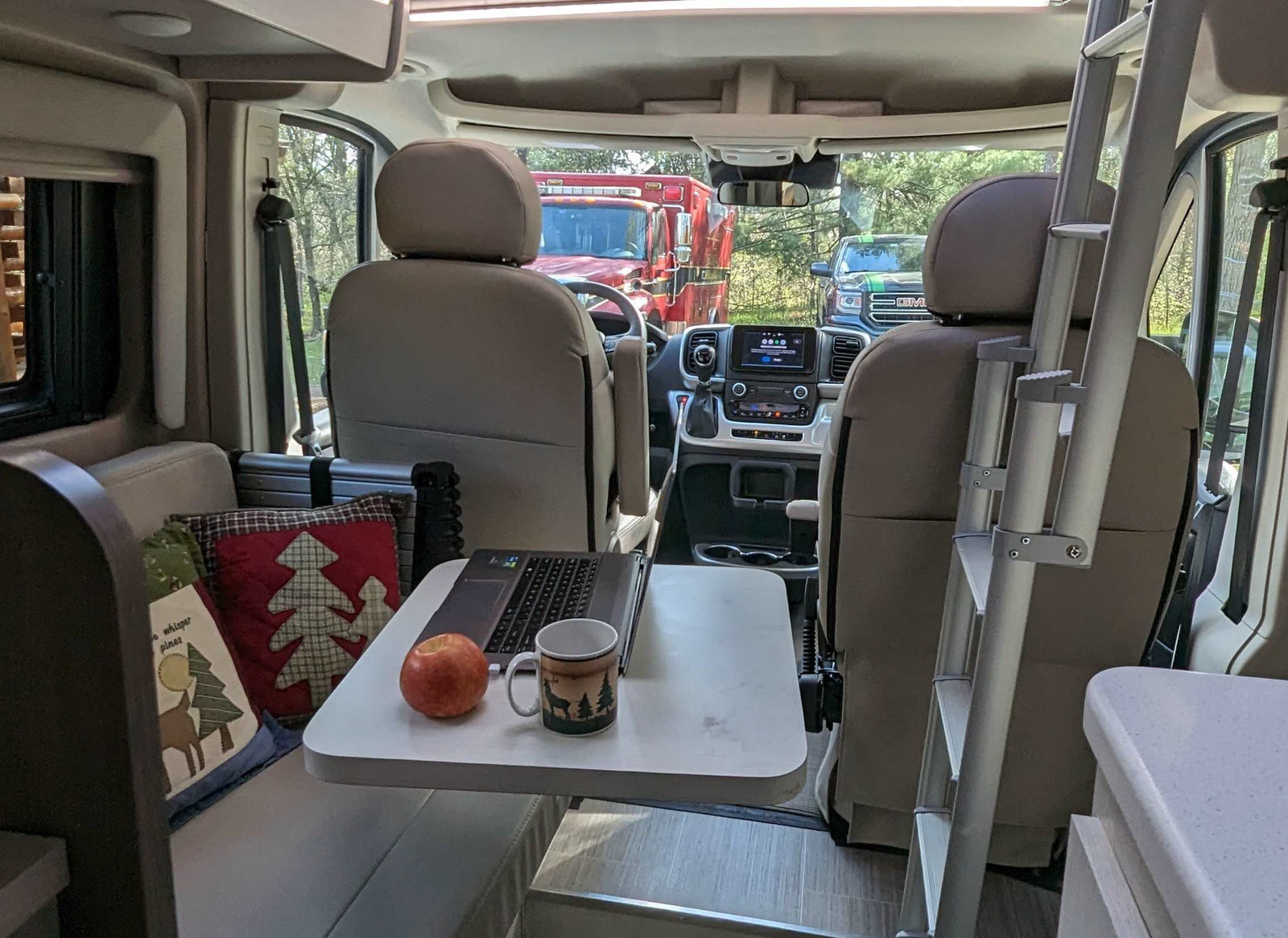 parked on asphalt by a lake with trees under a blue sky. Perfect for travel.|Rear view of a silver Thor Tellaro RV rental campervan with extended awning at a sunny wooded campsite