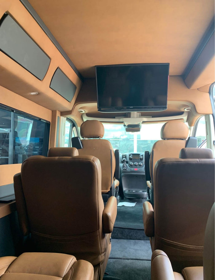 showcasing custom wheels & side graphics in a parking lot.|Spacious luxury van interior featuring tan leather captain's chairs. Perfect for an RV rental adventure.|Spacious RV rental interior with plush tan seats