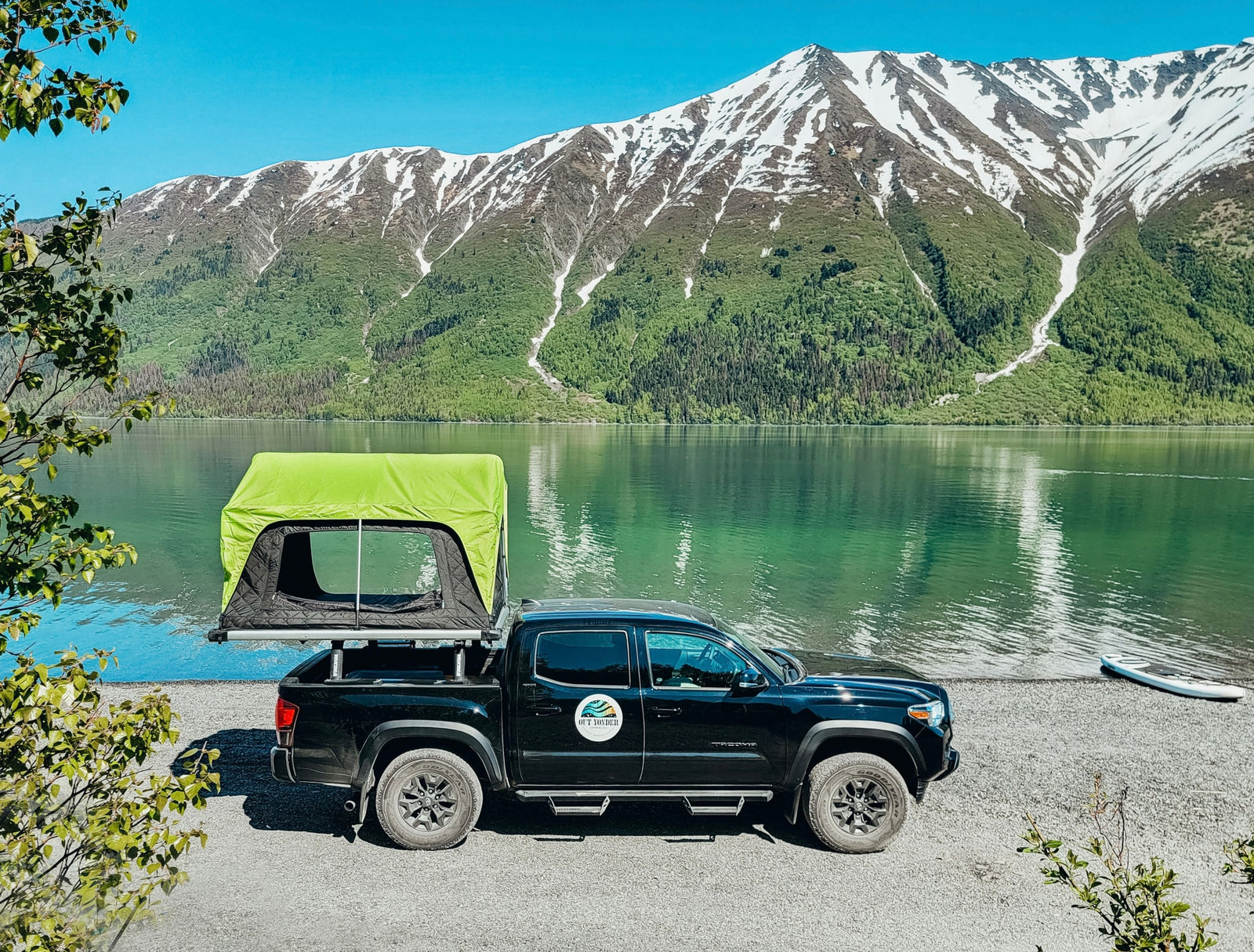 Adventure awaits! This **RV rental** truck with a rooftop tent offers lakeside **camping** with stunning mountain views. Perfect for outdoor travel.