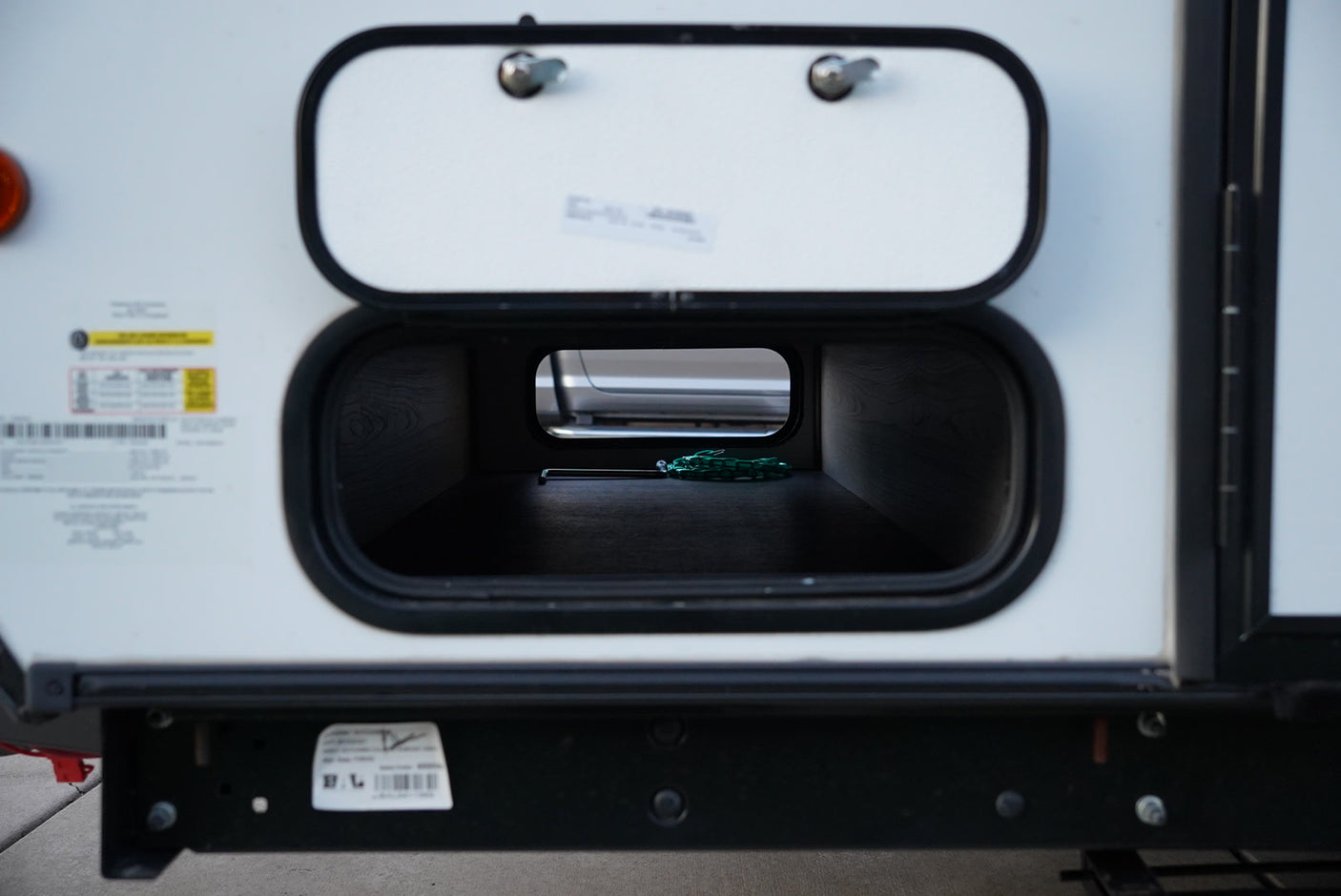 An RV rental's side with its main storage compartment open, revealing a green dragon-shaped hex key inside.