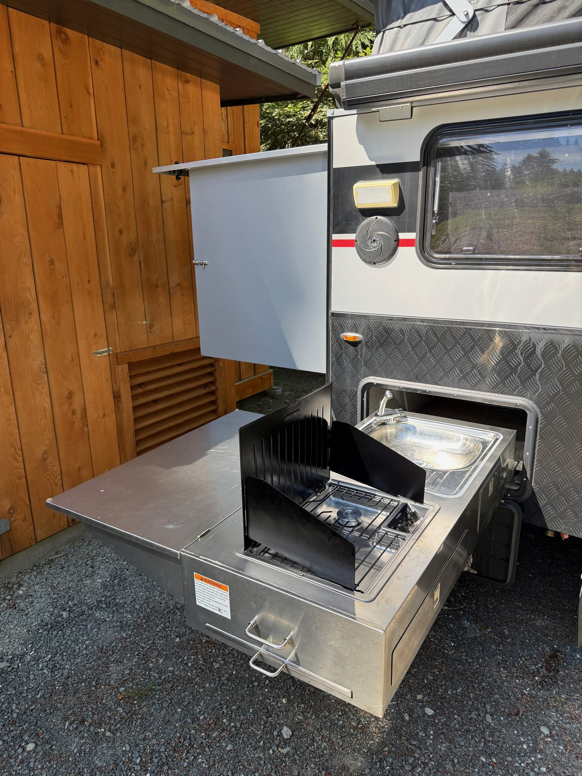Slide-out outdoor kitchen extended, with the Dometic propane cooktop, stainless sink and prep counter — photo 6