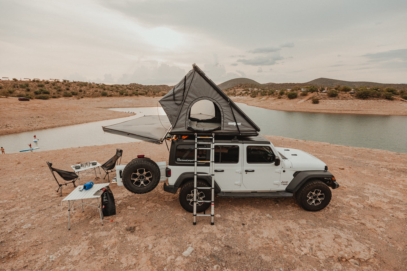 This RV rental features a Jeep with a rooftop tent, camping gear, and a lake view. Perfect for an outdoor adventure!