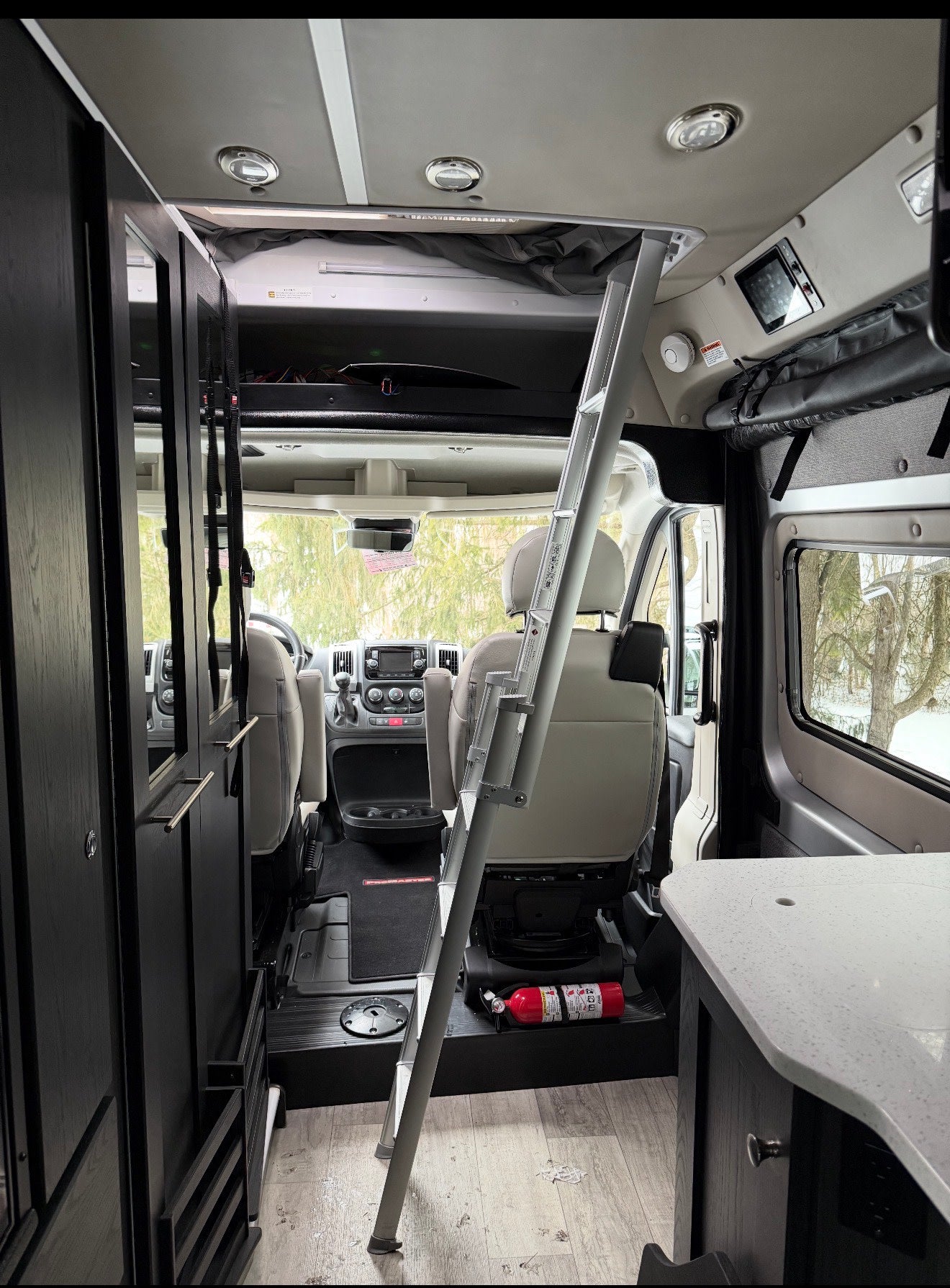 rv rental interior: front cabin, ladder to upper bunk, dark cabinetry, kitchen counter, and a visible fire extinguisher. — photo 12
