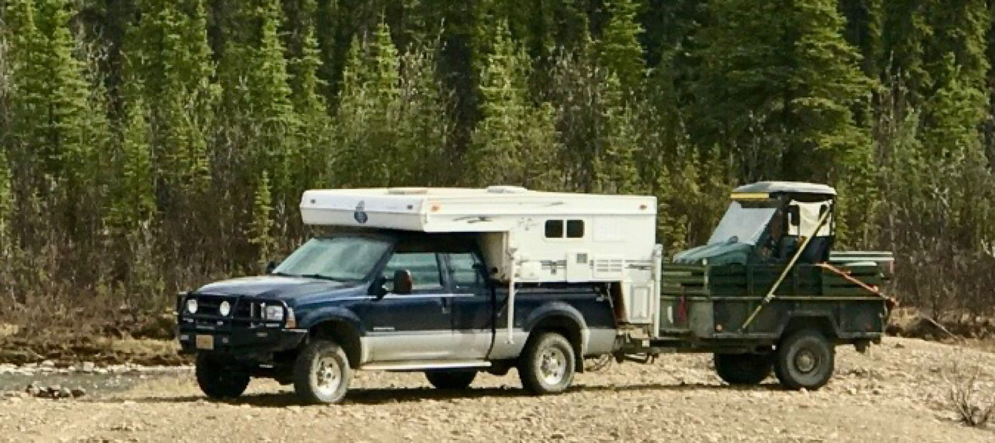 with a distant pipeline.|Overcast day camping in an RV rental truck camper by a tranquil forest river.|This RV rental