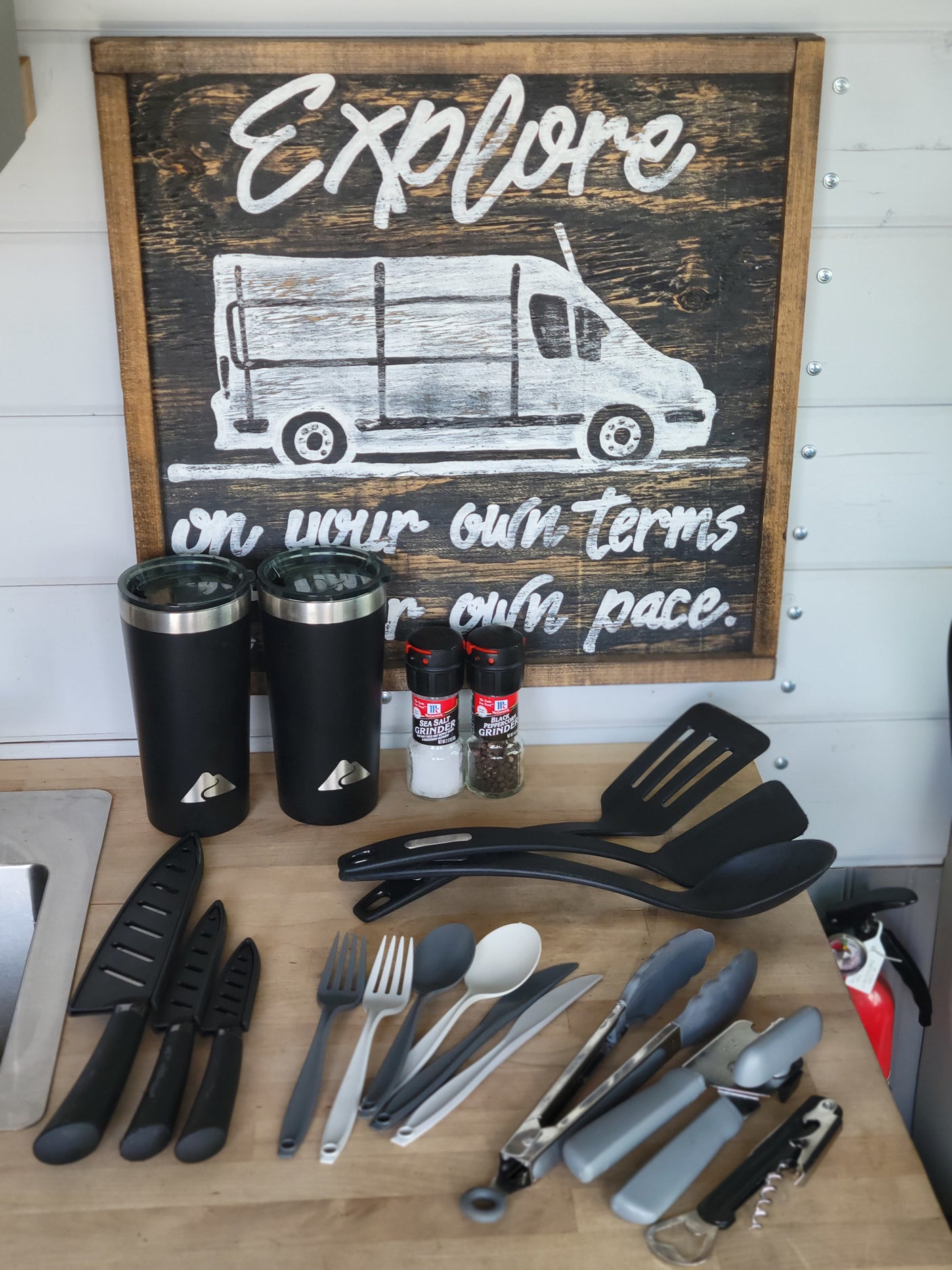 RV rental kitchen essentials: utensils, mugs, spices, and an "Explore" sign, ready for your adventures.