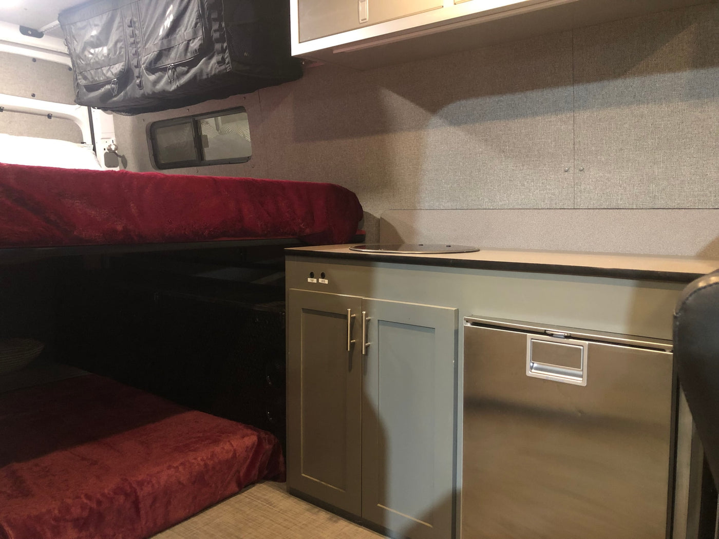 Inside an RV rental: features include bunk beds, a compact kitchenette with a fridge, and overhead storage. — photo 6
