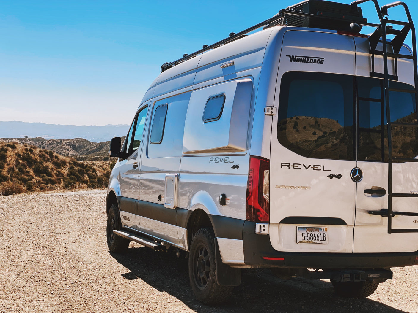 White Winnebago Revel 4x4 Sprinter RV rental on a dirt road. This off-road camper van is ready for scenic mountain adventures.