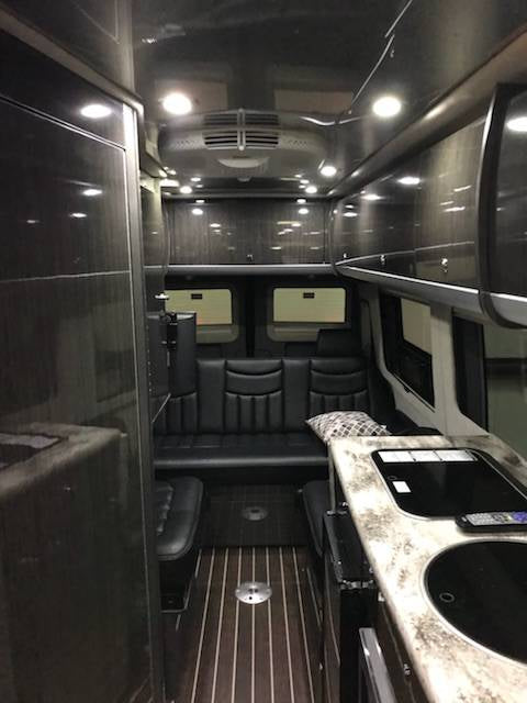 ready for your next adventure.|Inside a luxurious RV rental: rear black leather seating with patterned pillows