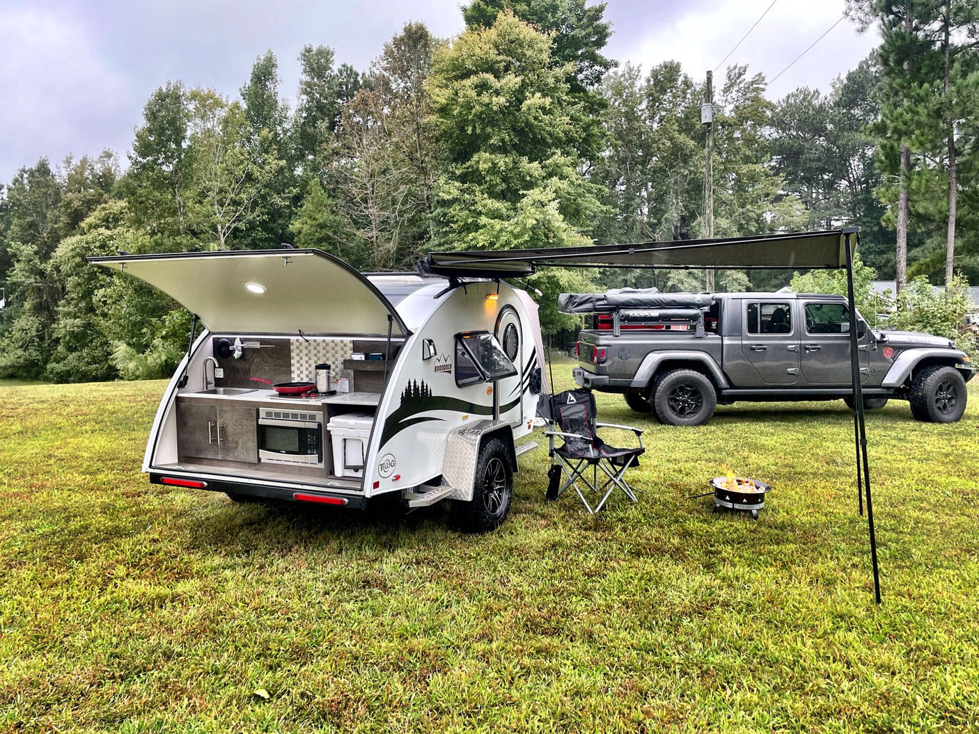 and part of a bed with white bedding.|Experience outdoor cooking with this RV rental teardrop camper kitchen: sink