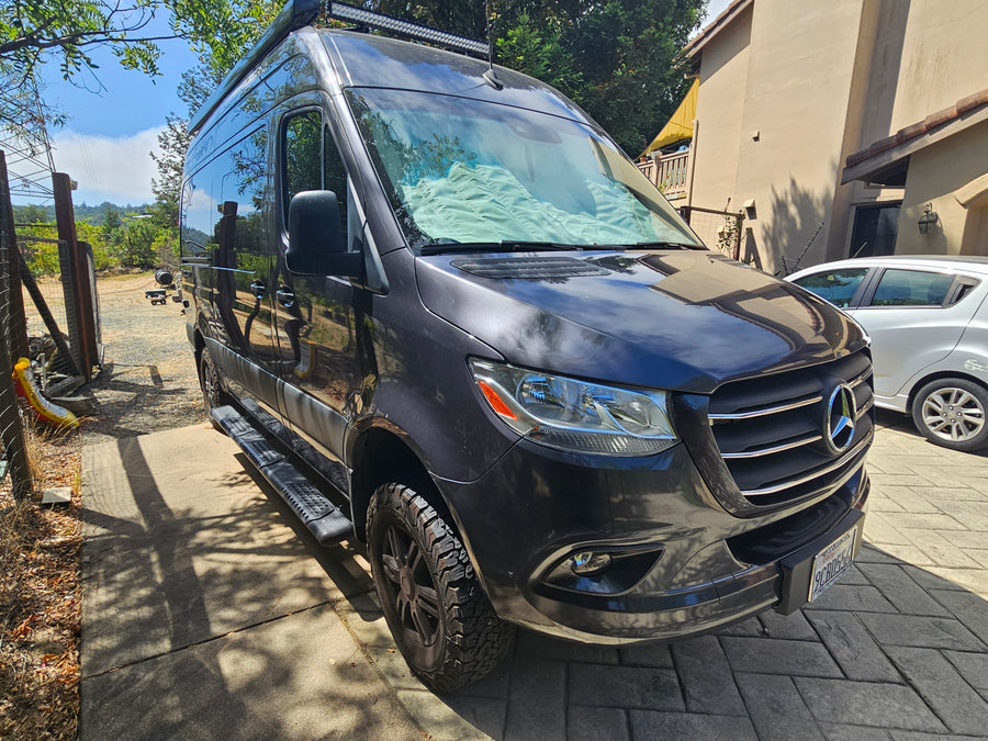 This gray Mercedes-Benz Sprinter rv rental is parked on a sunny driveway, ready for its next travel adventure.