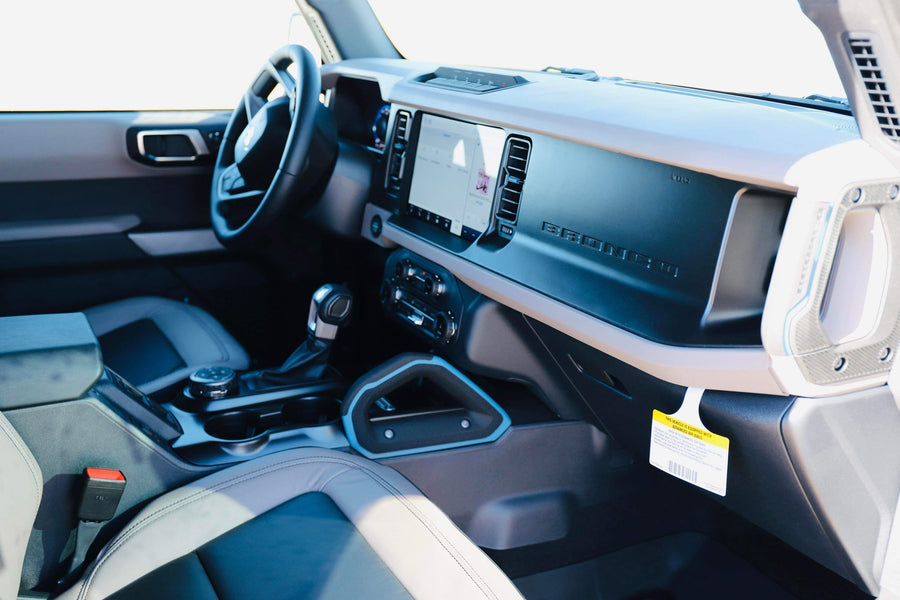 View inside a Ford Bronco, showing the dashboard, touchscreen, steering wheel, and gear shifter. Consider it for your rv rental.