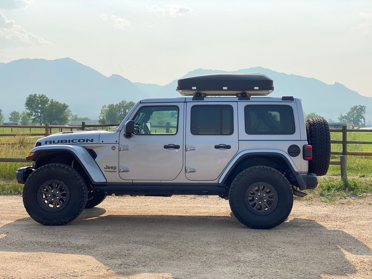 A silver Jeep Wrangler Rubicon with a roof box, ready for adventure. Perfect for an RV rental trip in the mountains.