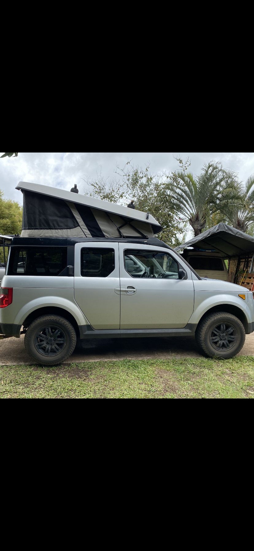 Silver Honda Element pop-top camper, ideal for rv rental adventures. Equipped with all-terrain tires for exploration.