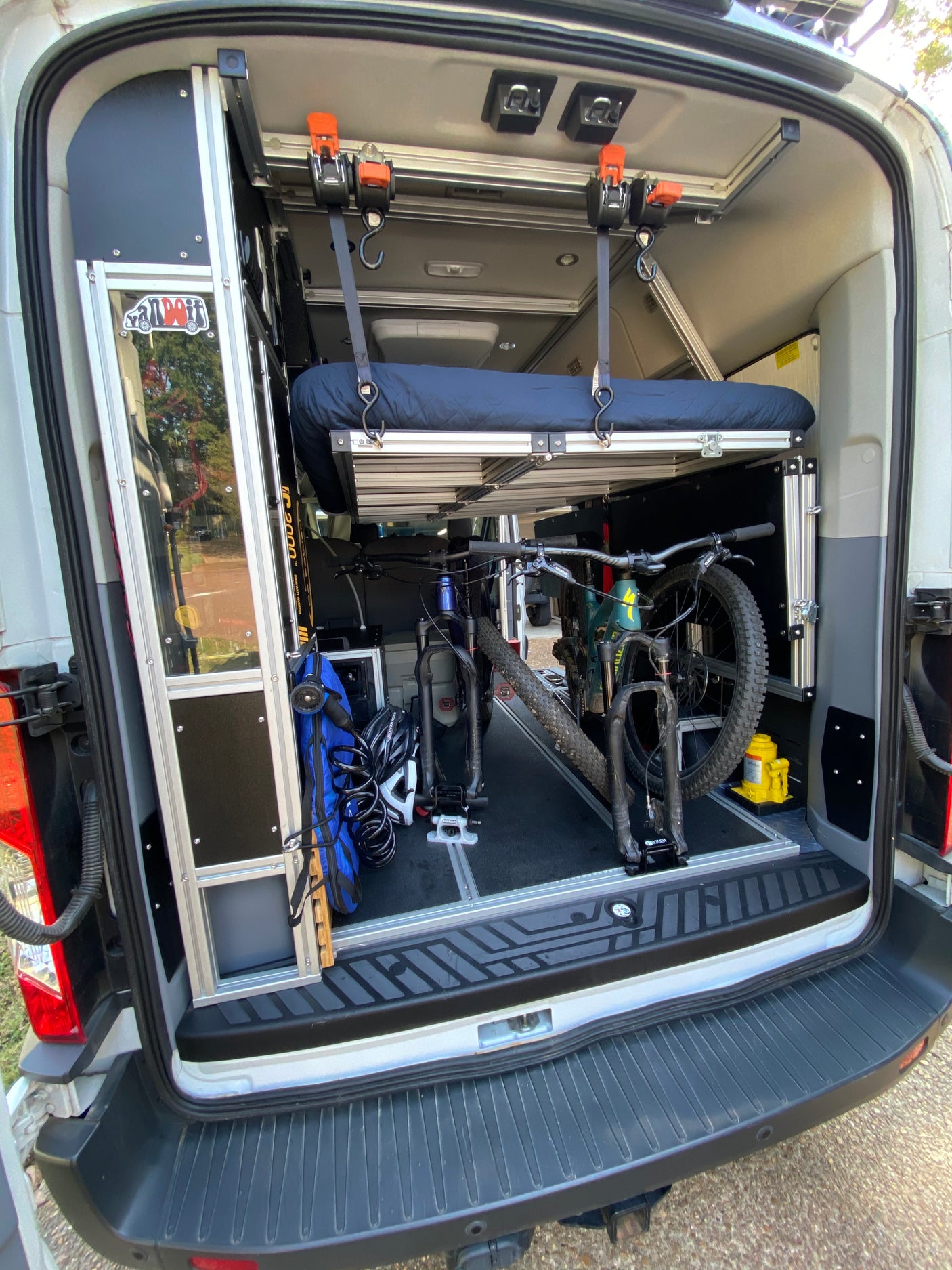 Inside an RV rental: custom camper van interior with elevated bed and two mountain bikes secured for travel.