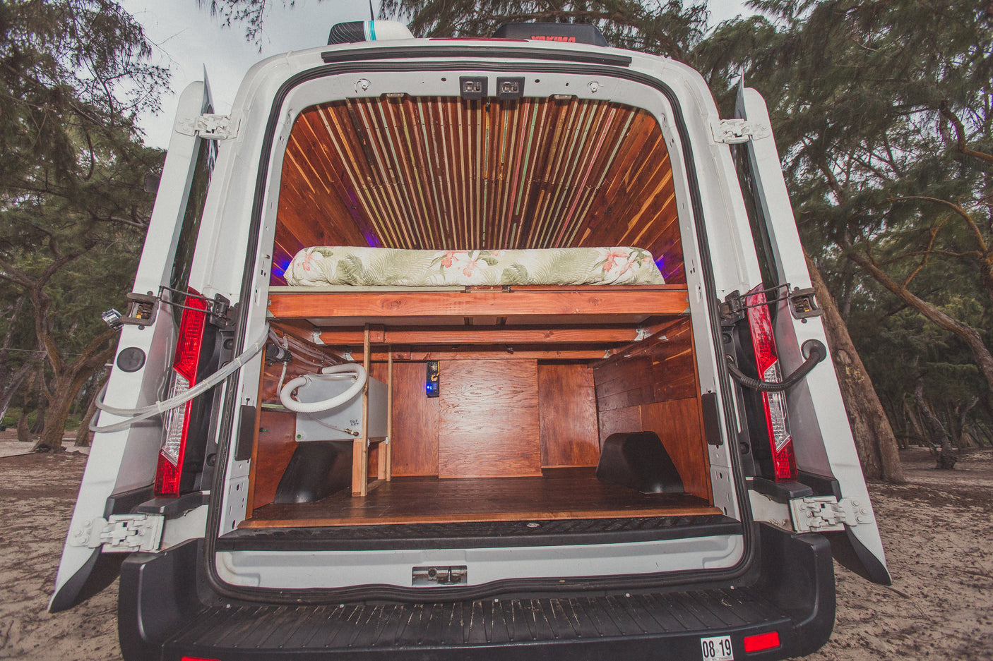 Inside a custom-built camper van, featuring a cozy bed, ample storage, and plumbing, ideal for your next rv rental adventure.