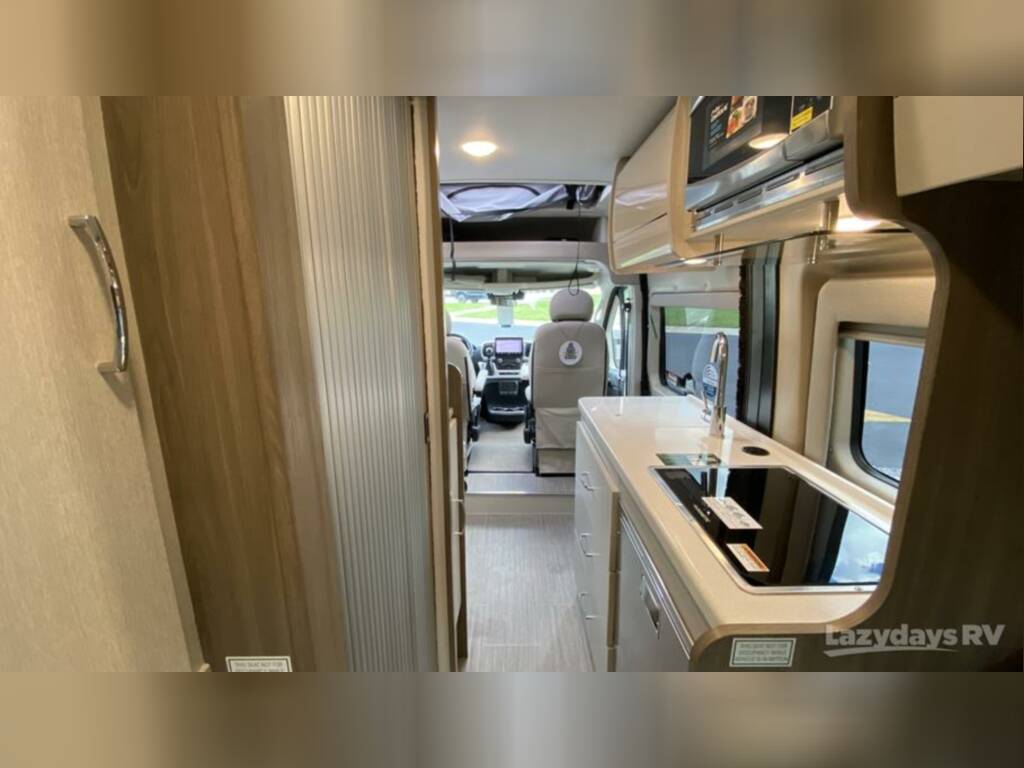 Inside a comfortable rv rental: modern kitchen with sink and stove, leading to the driver's cabin.
