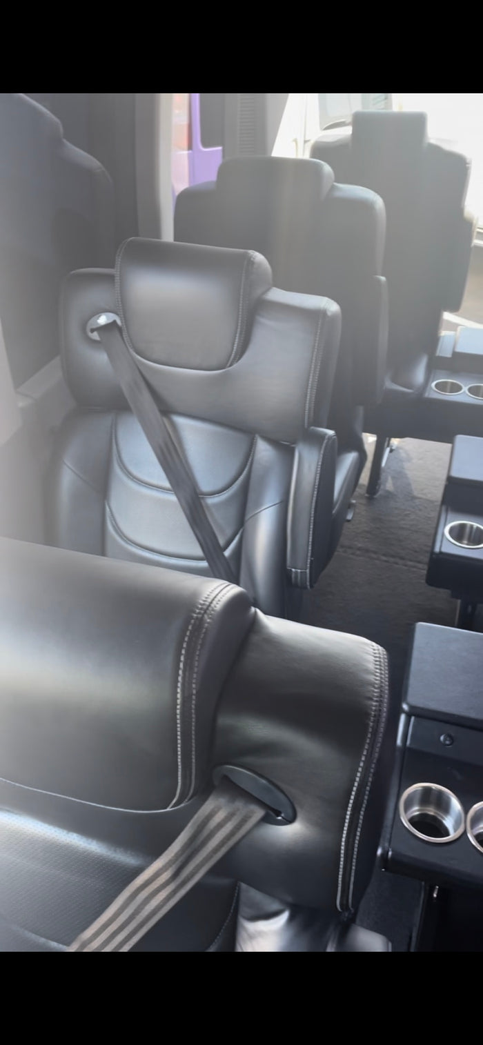 Plush black leather seats with seatbelts and built-in cup holders inside an RV rental, offering comfortable travel.