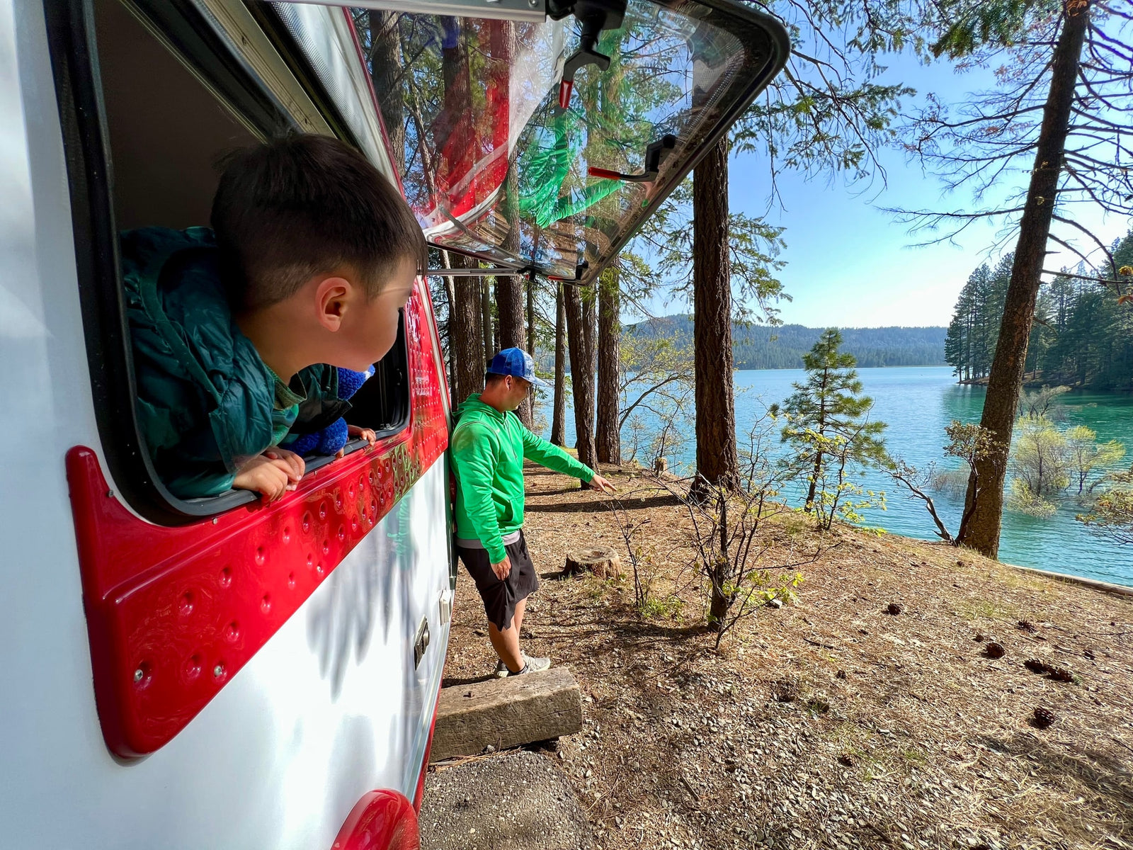 and large windows revealing a scenic campsite view.|Inside a cozy RV rental: a panda plush
