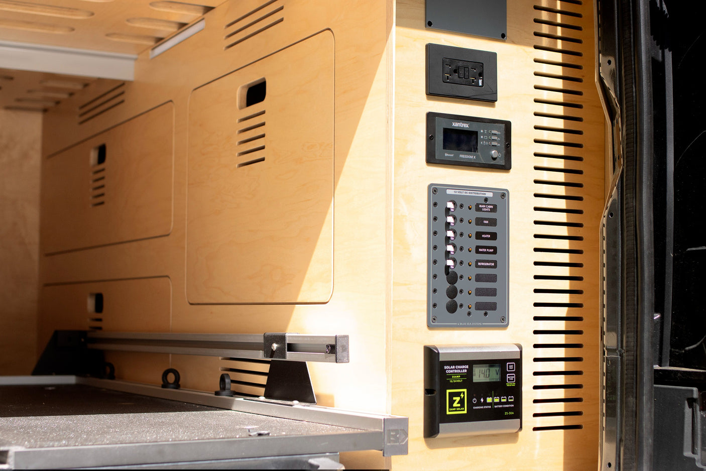 RV rental wood interior features power hub: Zamp Solar controller (14V) and 12V DC distribution for essentials.