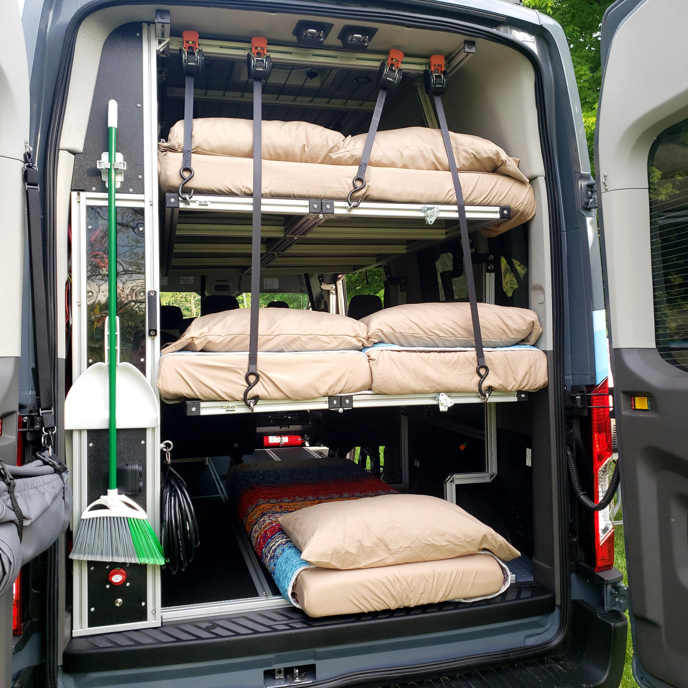 Inside an RV rental van: custom bunk beds for camping, neat storage for a broom & essentials.