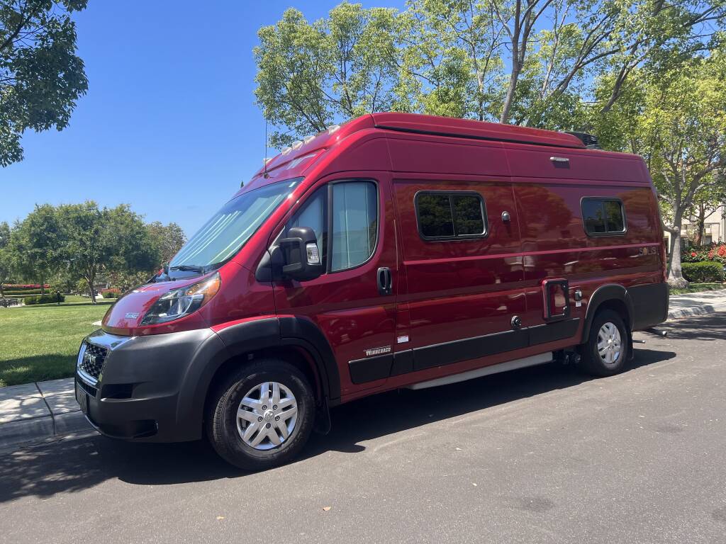 and both front seats visible.|RV rental interior: A bright camper van kitchen with a stove